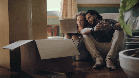 A couple with moving boxes is delighted about their new flat